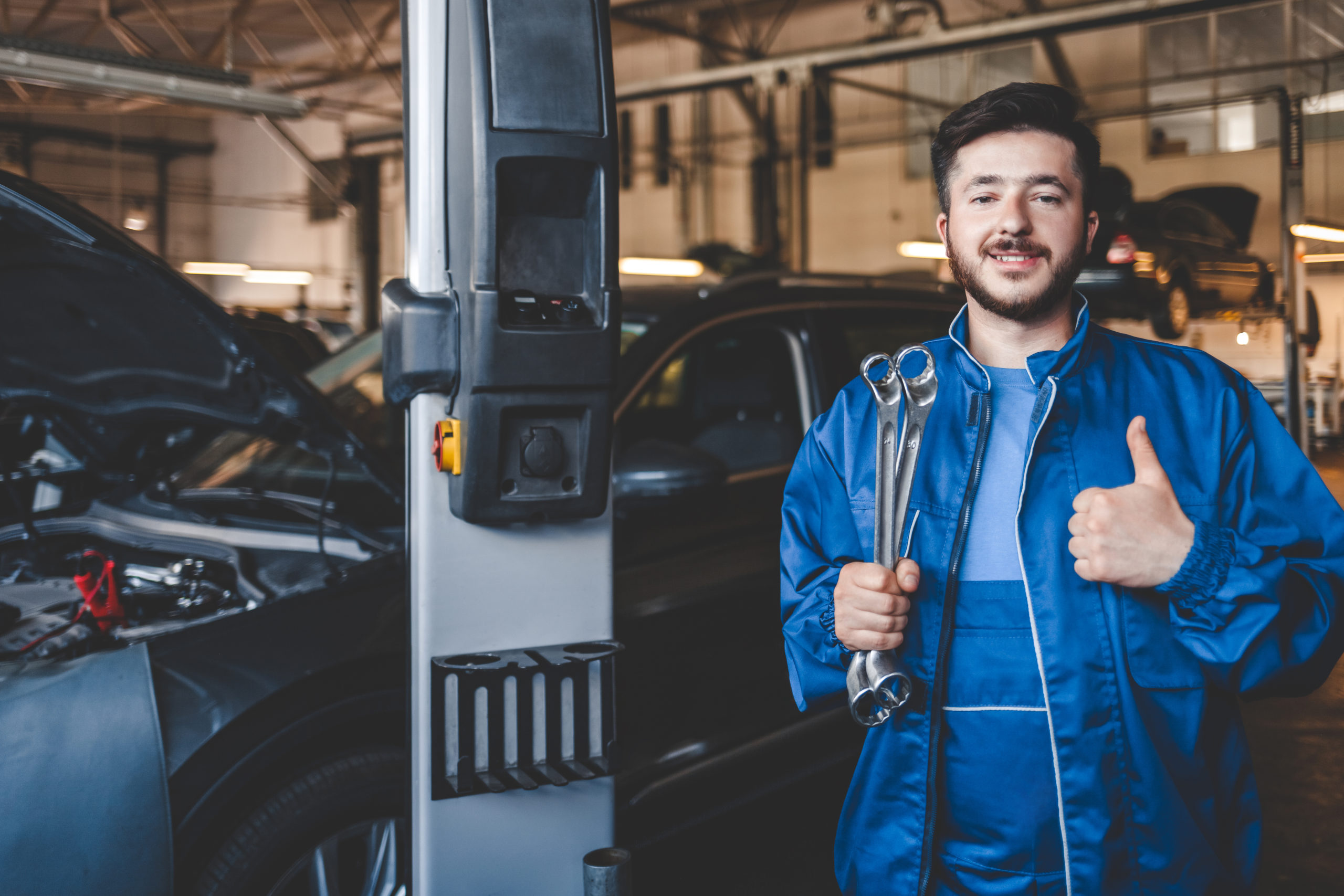 Car mechanic with wrench shows thumb up